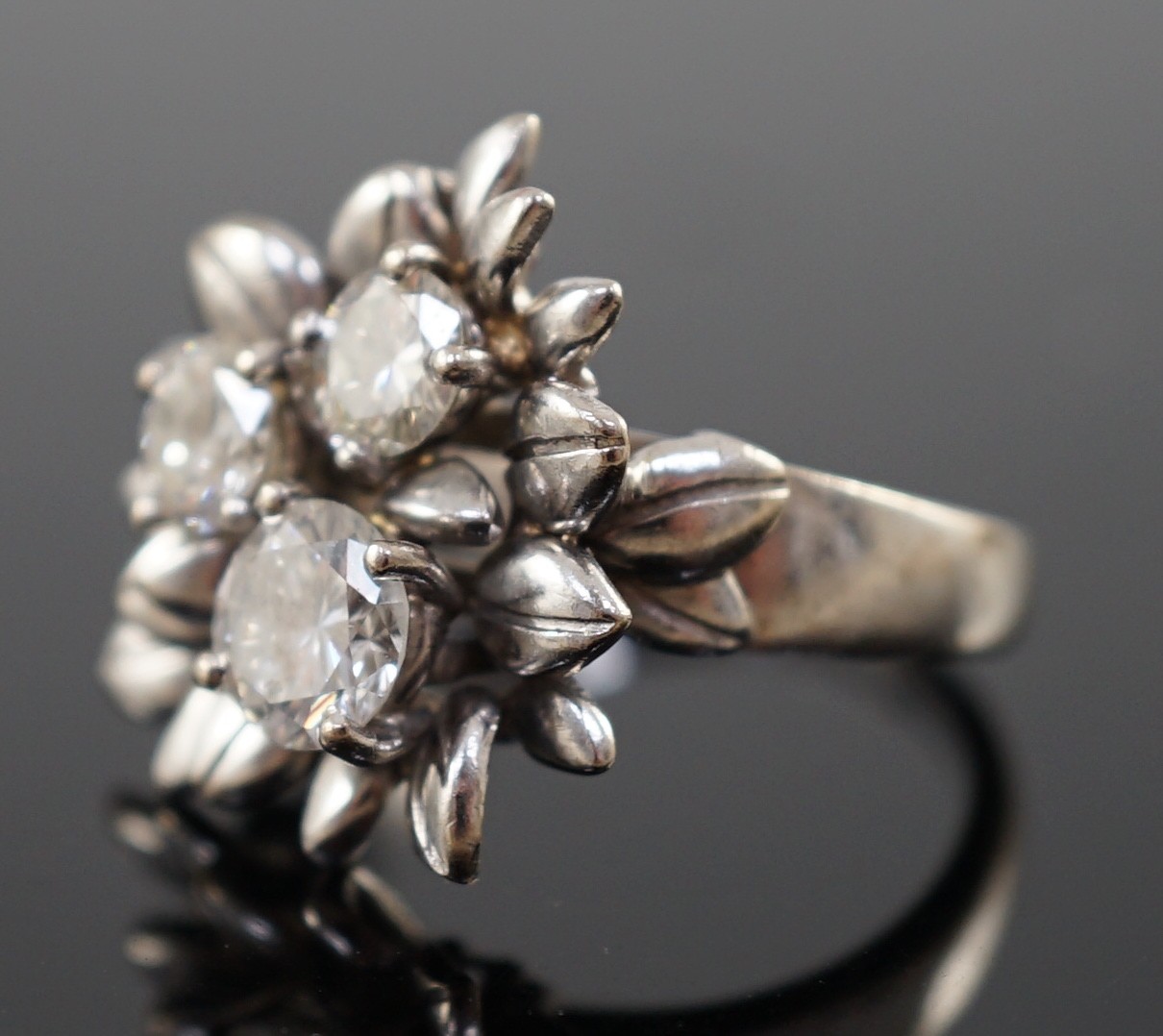 An 18ct white gold and three stone diamond set flowerhead ring